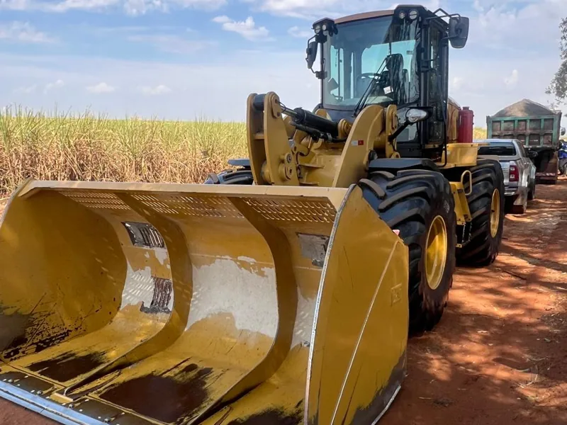 Pá carregadeira da frota da Bergo com caçamba de biomassa diante do canavial